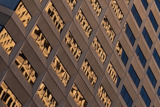 Brown building reflecting golden Transamerica Pyramid